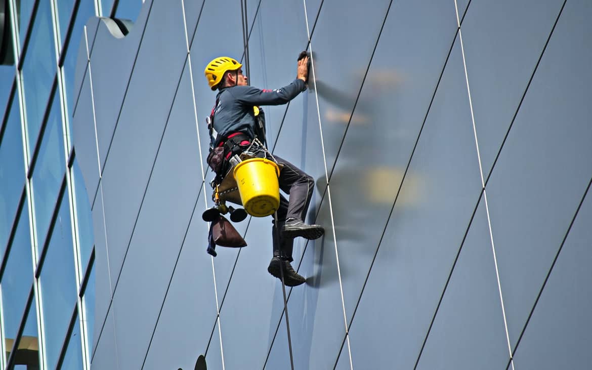 a man cleaning the outer side of a tall building
